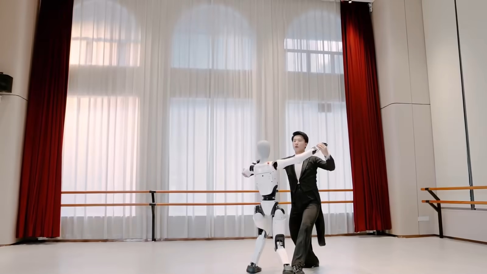 Humanoidni robot Walker C1 pleše z baletnim plesalcem v vadbeni dvorani, posnetek proizvajalca UBTECH