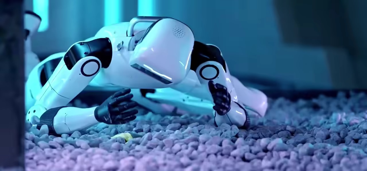 Robot OMNI se po vseh štirih hitro premika po prodnati podlagi v modro osvetljenem prostoru