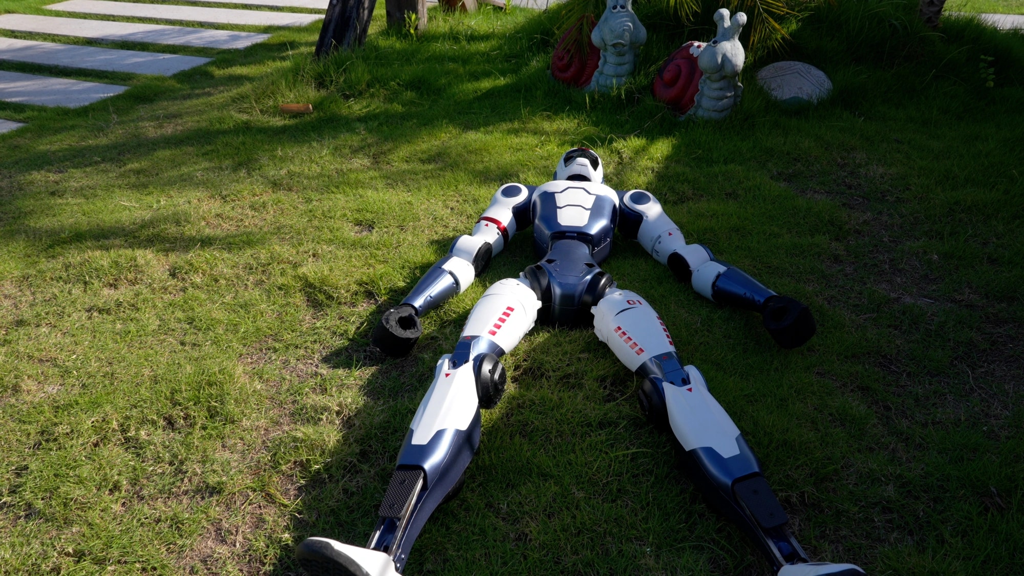 Robot R1 leži na travi pred dvigom na noge